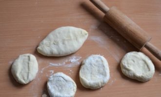 Enrotlleu cada peça en un pastís pla o modeleu-les amb les mans. El gruix dels pastissos és de 5-7 mm. Col·loqueu el farcit al centre dels pastissos, tanqueu bé les vores, donant una forma bonica als pastissos.