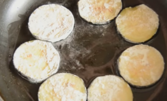 Frite as rodelas de berinjela na farinha em óleo fervente em fogo médio até dourar.