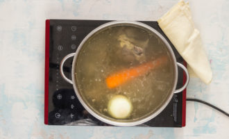 För att tillaga blandad kötthodgepodge enligt det klassiska receptet måste du laga buljongen enligt standardteknik. Lägg nöt- eller kycklingben och nötkött i kallt vatten och sätt på eld. Efter kokning, låt det koka i ett par minuter och häll vattnet ur pannan. Skölj köttet och benen, skölj pannan och häll på rent kallt vatten igen - ca 2 liter. Lägg hela den skalade löken och morötterna i pannan - även utan att skära dem. Koka den rika buljongen i ca 1,5 timme.