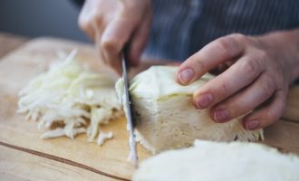 Finhakk hvitkålen med en kniv eller bruk en foodprosessor, hvis det passer deg mer. Knus så kålen litt med hendene og legg den i beholderen med løk og gulrøtter.