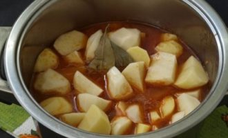 Cuando la carne se pueda pinchar fácilmente con un tenedor, añadir las patatas, las hojas de laurel, las especias para la carne y un poco más de agua hirviendo. Cocine a fuego lento el asado hasta que la carne y las patatas estén cocidas, tapadas. El fuego está bajo, remover de vez en cuando para evitar que se queme.