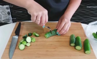 Como preparar rapidamente pepinos crocantes e levemente salgados com ervas e alho? Lave os pepinos, seque-os, corte-os longitudinalmente em 4 pedaços e coloque-os com cuidado em um saco plástico grosso e transparente.