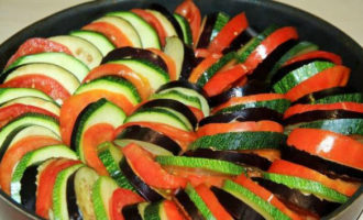 Læg ratatouille på saucen i lag: aubergine, tomater, zucchini osv. Begynd at lægge grøntsagscirklerne fra midten til kanterne, bevæg dig i en spiral - dette vil vise sig at være det smukkeste.