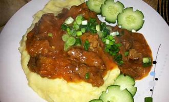 Am besten serviert man aromatisches Rindergulasch mit Bratensoße in einer Bratpfanne zusammen mit Kartoffelpüree und Gemüse.