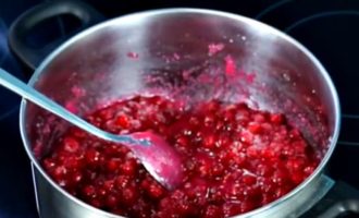 Giet rode bessenbessen in een pan en vul met water. We proberen op laag vuur te koken, zodat de bessen intact blijven. Zodra het kookt, giet je een derde van de suiker in de pan. Roer de inhoud van de pan voorzichtig door met een lepel en blijf koken totdat de suiker volledig is opgelost.