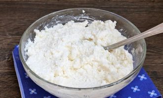 Tilsett salt og vanillin i beholderen med cottage cheese og mal blandingen grundig til den er mer eller mindre homogen uten klumper eller heterogene ostemasse. Etter dette, tilsett granulert sukker til blandingen og bland alt grundig.