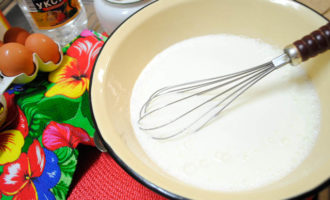 Riscaldare un po 'la quantità necessaria di kefir, versarla in una ciotola per impastare, aggiungere la soda, un pizzico di sale, lo zucchero e mescolare. Quindi rompi due uova nel kefir e mescola il tutto usando un mixer o una frusta.