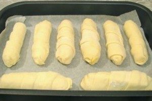 En una bandeja para horno forrada con pergamino, coloca las salchichas en la masa y mete al horno durante 30-40 minutos. Temperatura de horneado – 180 grados. Para que la superficie de la masa brille, puedes untar las salchichas encima con la yema de un huevo crudo.