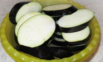 How to quickly and tasty cook eggplants in the oven? To begin, rinse the fresh eggplant thoroughly and cut it into slices about a centimeter thick. Place the circles in a large bowl and cover with purified, salted water for half an hour to remove the bitterness.