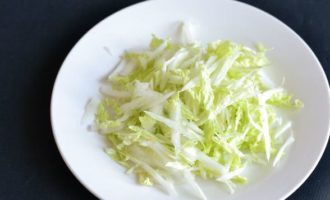 Lavamos a couve chinesa em água corrente, se necessário retiramos as folhas de cima se o seu aspecto não nos agrada. Pique o repolho finamente e coloque-o em um prato grande onde iremos recolher a salada. Corte o pepino fresco em fatias longitudinais.