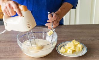 Then start beating the eggs and granulated sugar. You need to beat until a fluffy foam forms, then gradually start adding cubes of melted butter and continue beating.