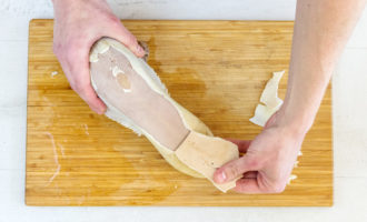 Place the tongue in a bowl of cold water for 4 minutes, then clean it, starting from the thick end - remove the skin. Again, dip the tongue into the broth and boil. Let's take it out to cool, and then cut the tongue into small slices.