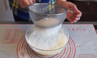 To make the pancakes airy, you need to loosen the stagnant flour a little. Therefore, we sift it through a sieve, adding it to the egg mass. Mix the dough.