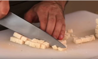 Um Cracker zu erhalten, müssen Sie die Kruste vom Weißbrot entfernen und die Krume selbst in gleich kleine Würfel schneiden. Den Knoblauch schälen und durch eine Knoblauchpresse in eine Pfanne mit erhitztem Olivenöl drücken. Den Herd ausschalten und abkühlen lassen.