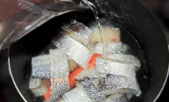 Pour 1.5 liters of cold water into the fish. Place the container on medium heat. Immediately add peeled carrots and onions to the broth.