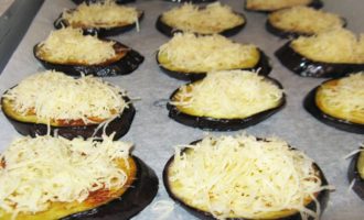 Pat the eggplants dry to remove excess oil and then line a baking tray with baking paper. Place eggplant mugs on it and sprinkle them with half of the finely grated hard cheese.