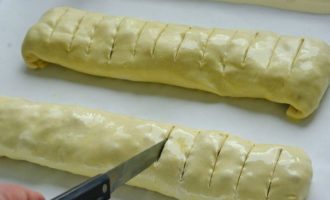 Then make several transverse cuts on the rolls with a sharp knife, which will allow you to cut the finished apple strudel into portioned pieces.