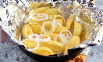 Take a baking sheet or baking dish and line the container with foil in two layers. Cut the potatoes into slices, circles or wedges - depending on your preference, and cut the onion into rings or half rings and place on foil.