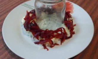 Take a flat, wide plate and place a half-liter jar or glass in the center. Place a layer of potatoes around the jar, lightly salt and pepper and coat with mayonnaise. Place half the beets, mayonnaise on top, then carrots and eggs, coat with mayonnaise.