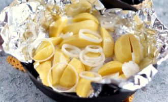 Polvilhe as batatas com sal e pimenta a gosto e adicione um pouco de azeite. Descasque e pique os dentes de alho ou passe-os num espremedor de alho e coloque-os em papel alumínio com as batatas para dar sabor ao prato.