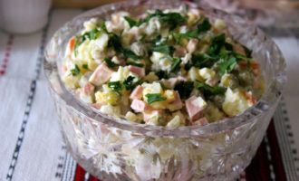 Séchez les légumes verts lavés, vous pouvez les diviser en deux. Ajoutez une moitié à la salade et remuez, laissez l'autre moitié pour la décoration. Transférez la salade Olivier dans un joli saladier et décorez joliment avec des brins de verdure. Placer au réfrigérateur pour laisser tremper pendant un moment.