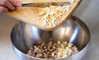 Hard-boil the eggs in salted water (takes exactly 10 minutes from the start of boiling water). Immediately remove them with a slotted spoon into cold water to make cleaning easier. Remove the shells from the cooled eggs, chop them finely and add to the cubes of smoked meat.