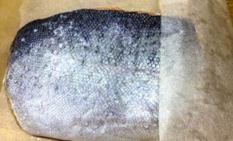 Now we need baking paper. Sprinkle it with a mixture of salt and sugar, and place one piece of trout on it, scales down. Then we place another one on this piece, now with the scales facing up. Fold the paper into an envelope. Transfer to a container and put in the refrigerator for 1 day.