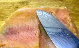 We take it out, remove the excess layer of salt from the fish and cut the fillet into several strips.