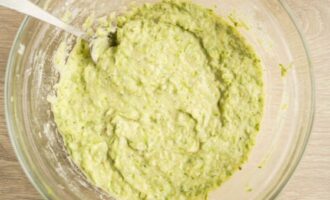 Add salt, ground black pepper to the prepared zucchini, chop the garlic cloves. Mix. The ingredients already indicate the approximate weight of grated and squeezed zucchini. Sift flour and soda into zucchini. Mix carefully.