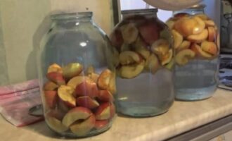 Plaats de appels in voorgesteriliseerde containers - potten van drie liter. Giet er hete siroop over, dek af met deksels en laat 15 minuten staan. Giet na een tijdje de siroop uit de potten en kook opnieuw.