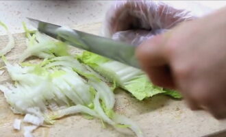 Hugasan at tuyo ang mga dahon ng Chinese cabbage. Kung may matitigas na ugat, mas mabuting putulin ang mga ito. Gupitin ang repolyo sa mga dahon sa manipis na mga piraso. Bilang opsyon, sa halip na Peking lettuce, perpekto ang Iceberg lettuce.