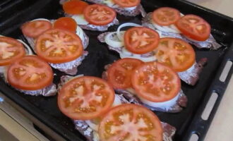 Place onion rings and tomato slices on the prepared meat, distributing them evenly over the entire surface.