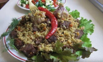 Carefully place hot beef pilaf on plates, garnish with herbs if desired and serve.