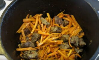 Cut the peeled carrots into thin strips. By this time the meat will be evenly fried. Place the chopped carrots in the cauldron with the meat and fry, stirring occasionally, until golden brown.