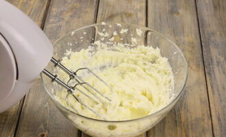 Let's move on to preparing the creamy layer. Mix room temperature cream cheese in a bowl with sugar and beat everything together with a mixer at high speed until the sugar grains dissolve.