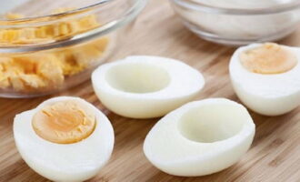 We peel the eggs and separate them into yolks and whites. Grind the whites on a coarse grater and place on top of the layer of cucumbers.Apply a second mesh of mayonnaise to the eggs.