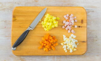 Now cut the boiled vegetables into small cubes and cut the eggs and sausage in the same way.