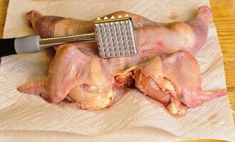 Comment cuisiner le poulet au tabac selon la recette classique ? Nous lavons le poulet, coupons l'excès de peau et les zones grasses, puis le séchons soigneusement avec une serviette en papier. Placer la carcasse côté poitrine vers le haut et la couper le long de la poitrine sans toucher le dos. Nous ouvrons la carcasse en une couche et la retournons. Couvrir le poulet d'un film alimentaire et battre avec un marteau de cuisine. 