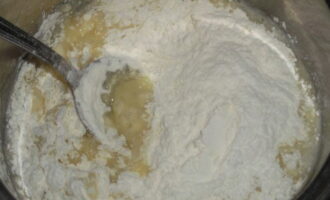 Pour pre-sifted flour into boiling water and oil. In this case, the resulting thickening mass in the pan must be actively and continuously stirred with a spoon or spatula, avoiding the formation of lumps. You can also use a mixer for kneading - this will make manual work easier, since the mass will form quite dense.