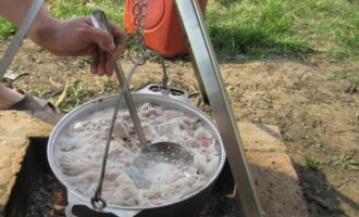 Das Fleisch etwa eine Stunde lang über dem Feuer garen. Entfernen Sie den Schaum regelmäßig.