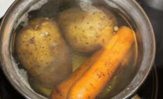 Upang maghanda ng Mimosa salad na may de-latang isda ayon sa klasikong recipe, ihanda ang lahat ng mga sangkap. Hugasan ang mga patatas at karot, ilagay ang mga ito sa isang kasirola, takpan ng tubig at lutuin hanggang malambot.