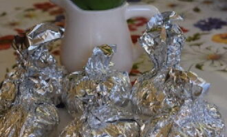 We wrap the potatoes in foil with the shiny side inward, lifting the edges of the foil up and connecting them - this way it will be easy to unfold the structure later. The potatoes should be left in such a position that the cut with butter is on top under the gathered edges of the foil. Place the potatoes in foil on a baking sheet and place in an oven preheated to 190 degrees. Bake for twenty minutes.