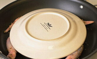 Cover the carcass with a plate of suitable diameter, placing it bottom up. If you have a special lid with a press, it’s time to use it instead of a plate.