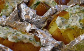 Take the potatoes out of the oven and place a spoonful of the prepared sauce into the cut. Serve the baked potatoes directly in foil.