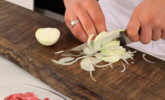 Peel the onions and cut them into thin half rings.