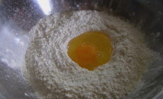 Pour the flour into a deep bowl and break the egg into it.