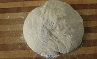 When the dough becomes very thick, sprinkle the table with flour and place the dough on it, continue kneading with your hands. Leave the dough for 15 minutes so that it rises a little and you can make pies.