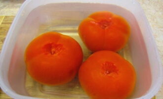 Select meaty tomatoes. Wash them thoroughly in cool running water, remove the stem, and then place them in a deep container and pour pre-prepared boiling water for about a minute. Then place the tomatoes in cold water and carefully remove the skins.