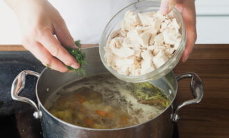 After the potatoes become soft, chop the boiled chicken meat and place it in the pan. We also add chopped dill and a peeled and chopped garlic clove. Cook for 3 minutes and remove from the stove.