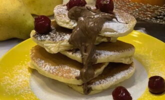 Decorate fluffy pancakes as you wish. I used chocolate spread, powdered sugar and cherries. Serve classic milk pancakes with freshly brewed aromatic tea or coffee.